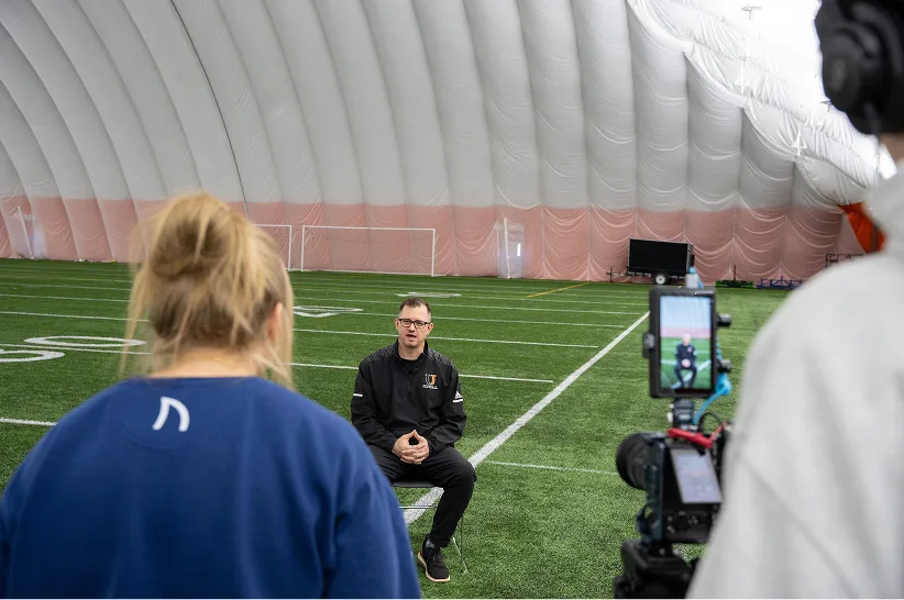 The AdShark video team filming an interview on an indoor football field
