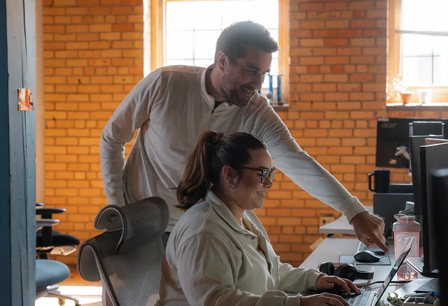 Two AdShark team members reviewing work at a desk in the office