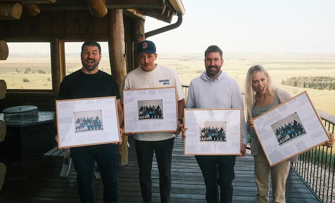 Four AdShark team members on a deck holding framed team photos