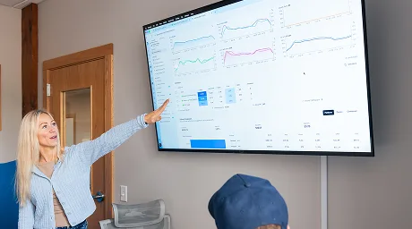 An AdShark strategist presenting campaign performance dashboards on a wall screen