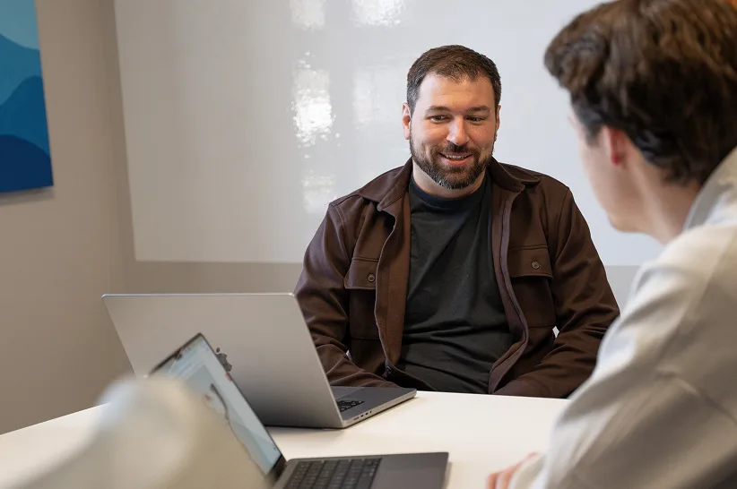 An AdShark strategist talking with a client across a table of laptops