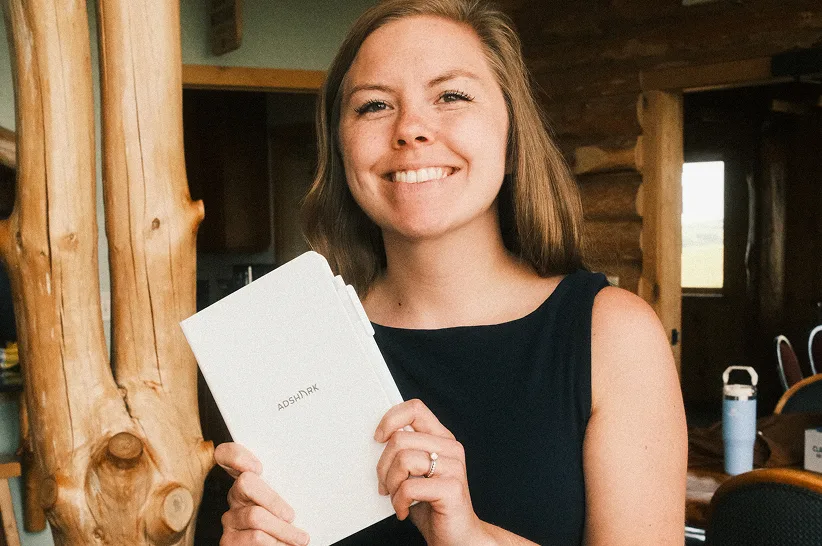 An AdShark team member holding a branded notebook at a company retreat