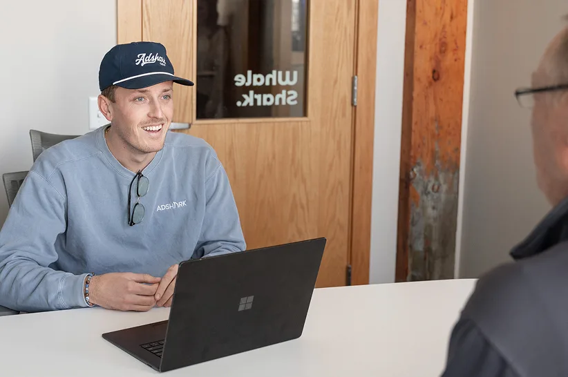 An AdShark strategist meeting a client at a laptop in the Fargo office